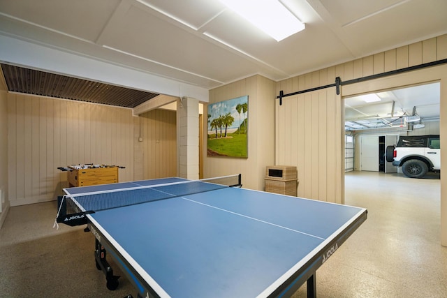 rec room featuring a barn door and wooden walls