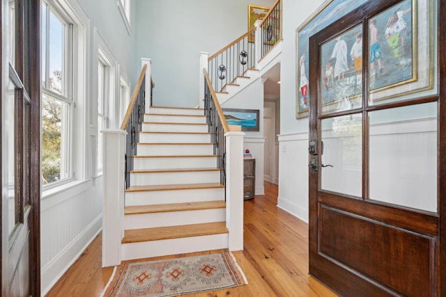 stairway with wainscoting, a decorative wall, and hardwood / wood-style floors