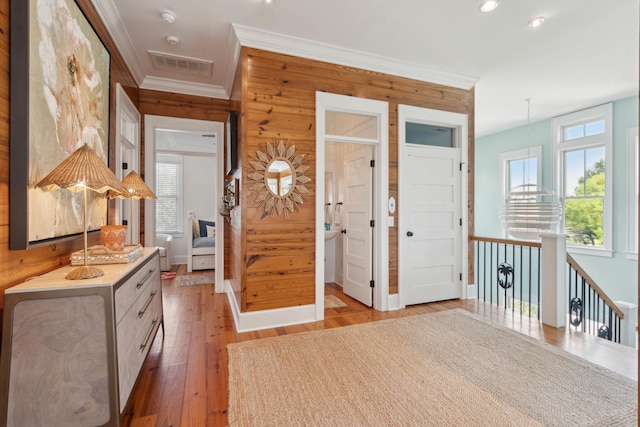 entrance foyer featuring crown molding, wood walls, visible vents, recessed lighting, and light wood-type flooring