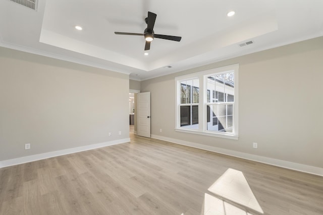 unfurnished room featuring a tray ceiling, ceiling fan, and light hardwood / wood-style floors