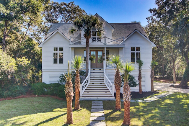 view of front of house with a balcony, french doors, and a front yard