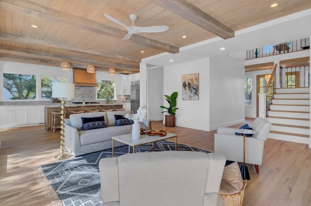 living room with ceiling fan, sink, beam ceiling, light hardwood / wood-style flooring, and wooden ceiling