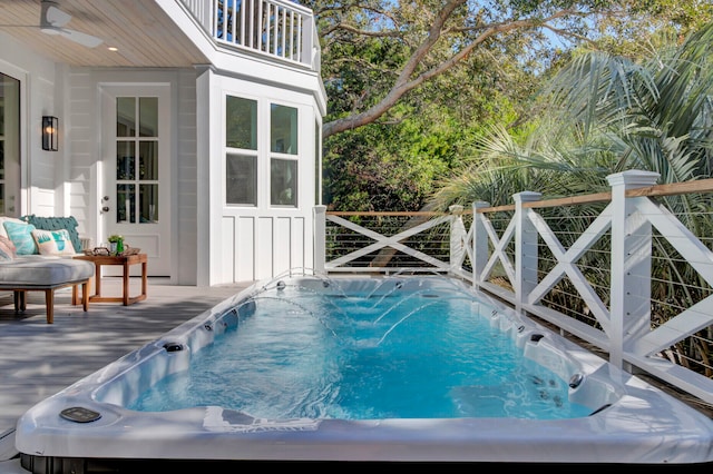 view of swimming pool featuring ceiling fan and a wooden deck