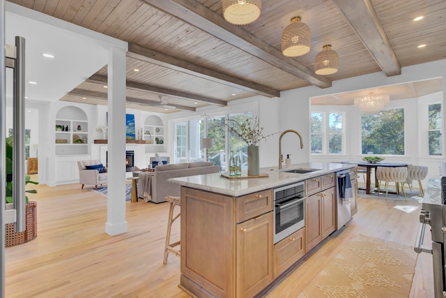 kitchen with a healthy amount of sunlight, an island with sink, appliances with stainless steel finishes, and sink