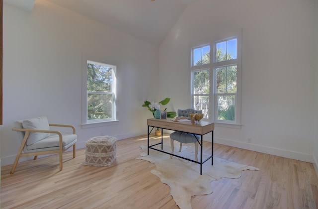 home office with high vaulted ceiling and light wood-type flooring