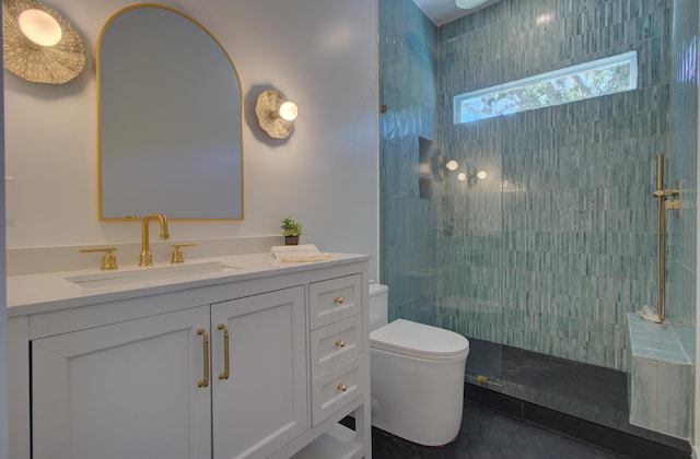 bathroom featuring a tile shower, tile patterned flooring, vanity, and toilet