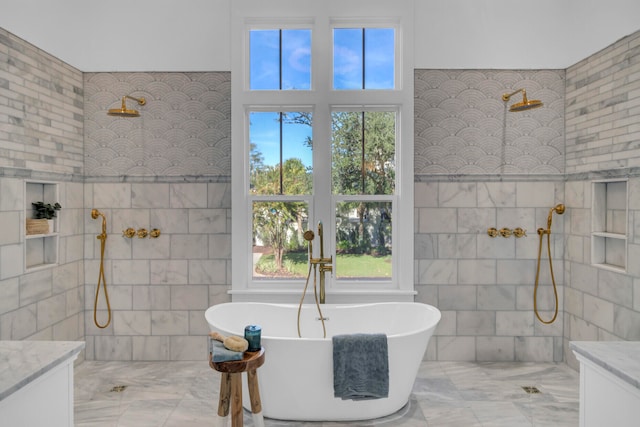 bathroom with vanity, tile walls, a healthy amount of sunlight, and plus walk in shower