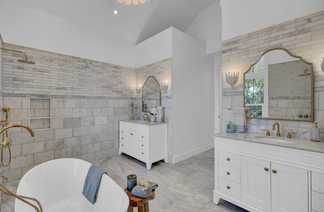 bathroom featuring a washtub, vanity, vaulted ceiling, and tile walls