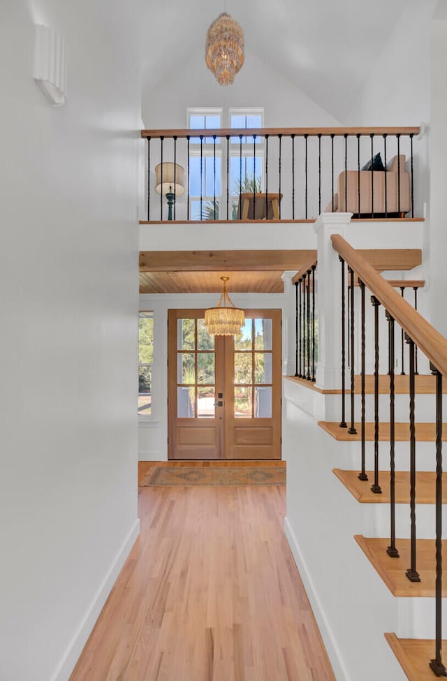 entryway with vaulted ceiling, a chandelier, hardwood / wood-style flooring, and french doors