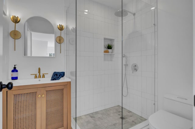 bathroom with a tile shower, vanity, and toilet