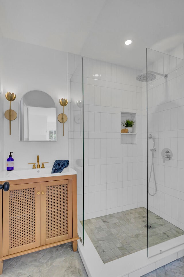 bathroom with a tile shower and vanity