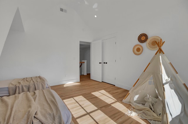 bedroom with high vaulted ceiling and light hardwood / wood-style floors