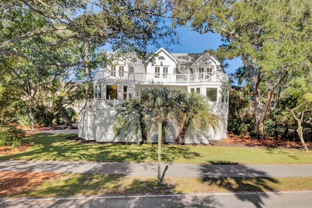 view of front facade with a balcony, covered porch, and a front yard