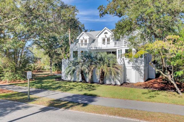 view of front of house with a balcony and a front lawn