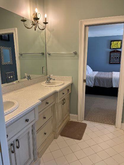 bathroom with double vanity, a notable chandelier, ensuite bath, and a sink