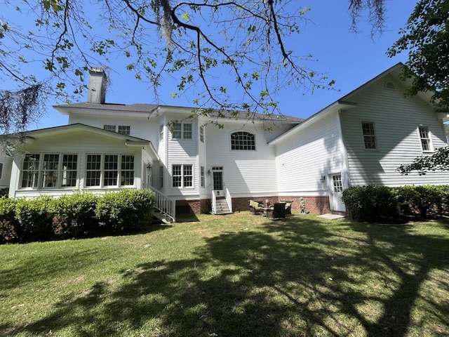 rear view of house with a chimney, entry steps, a yard, central air condition unit, and a sunroom
