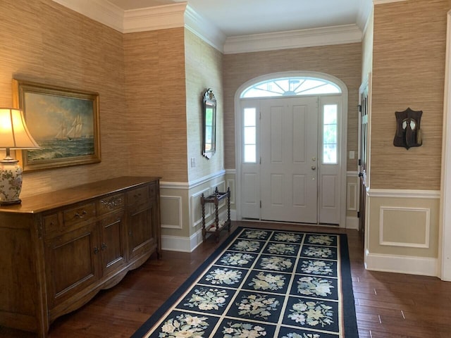 entrance foyer featuring ornamental molding, wallpapered walls, dark wood-style flooring, and wainscoting
