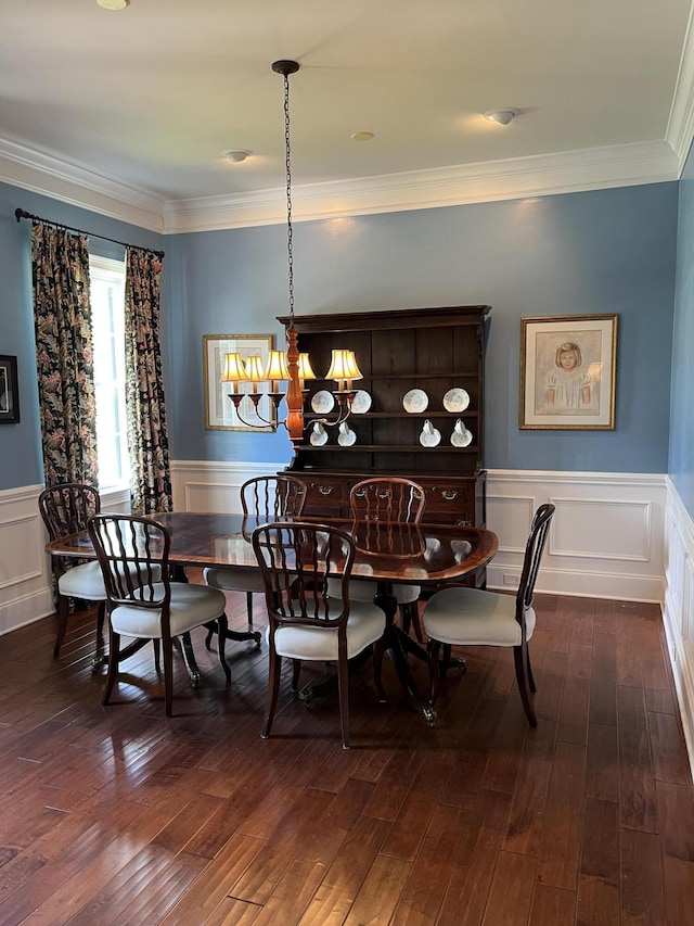 dining space with ornamental molding, a notable chandelier, wainscoting, and dark wood-style floors