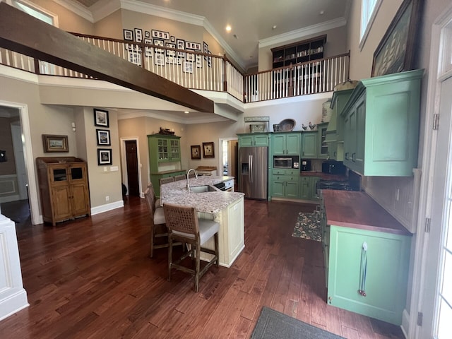 kitchen featuring dark wood-type flooring, a sink, appliances with stainless steel finishes, a towering ceiling, and green cabinets