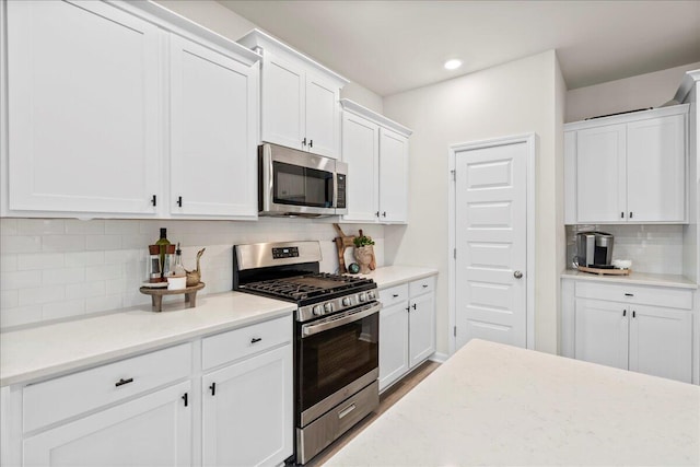 kitchen featuring white cabinets, backsplash, and appliances with stainless steel finishes