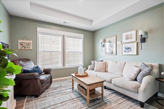 living room featuring light wood-type flooring and a tray ceiling