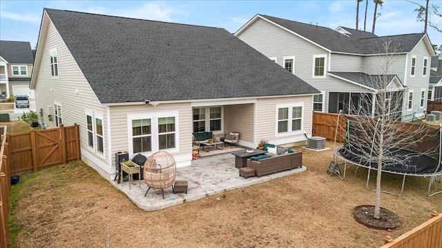 rear view of house featuring a patio area, an outdoor living space with a fire pit, central AC, a lawn, and a trampoline