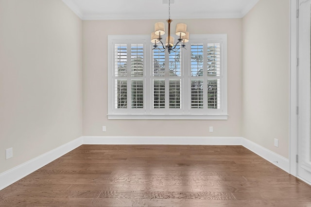 unfurnished dining area featuring baseboards, crown molding, an inviting chandelier, and wood finished floors