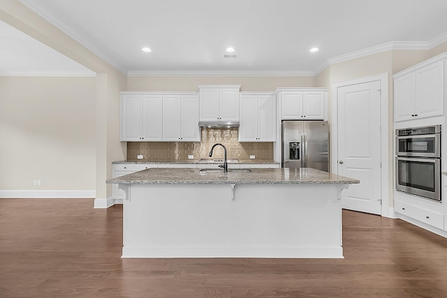 kitchen with dark wood finished floors, appliances with stainless steel finishes, an island with sink, and a sink