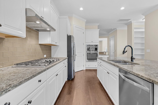 kitchen featuring under cabinet range hood, stainless steel appliances, ornamental molding, and a sink