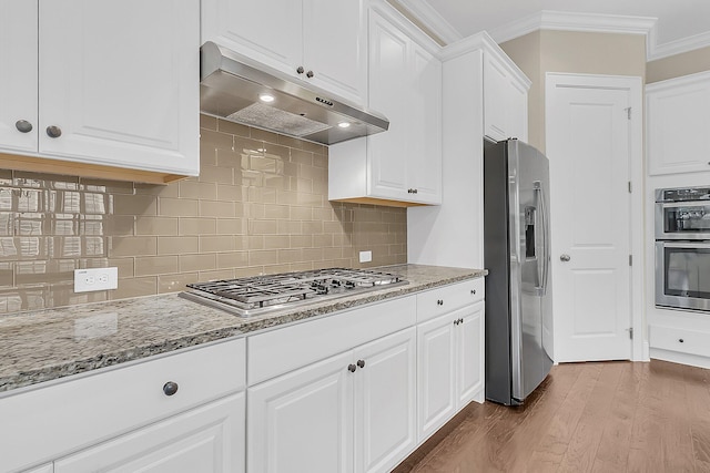 kitchen featuring crown molding, under cabinet range hood, stainless steel appliances, wood finished floors, and white cabinetry