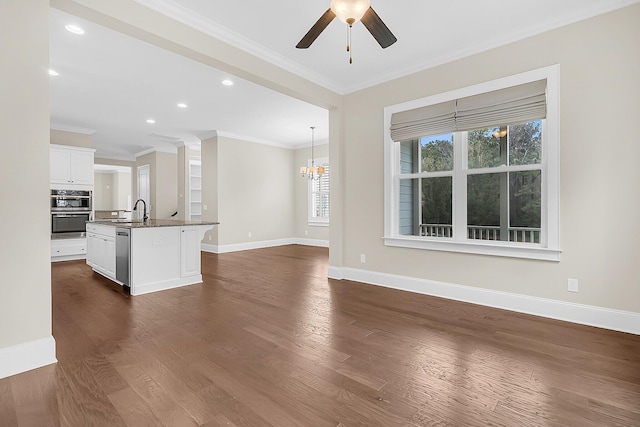 unfurnished living room featuring crown molding, dark wood-type flooring, baseboards, and a sink