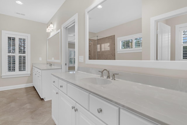 full bath featuring a sink, visible vents, two vanities, and a tile shower