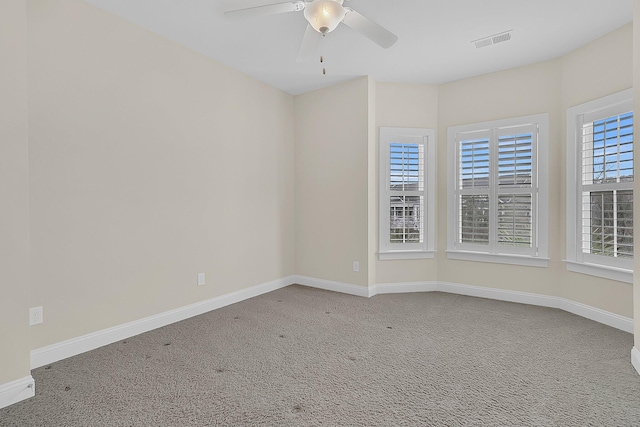 spare room with carpet, baseboards, visible vents, and ceiling fan