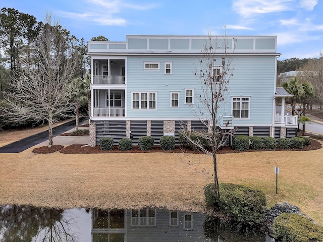 back of house featuring a balcony and a lawn