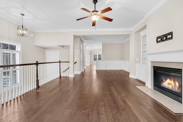 unfurnished living room with a fireplace with flush hearth, built in features, crown molding, and wood finished floors