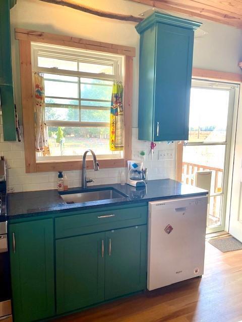 kitchen featuring dishwasher, backsplash, sink, and wood-type flooring