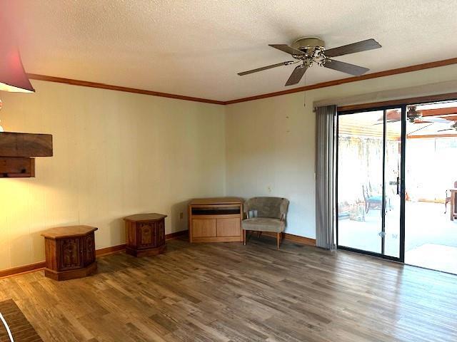 unfurnished room with ceiling fan, wood-type flooring, a textured ceiling, and ornamental molding