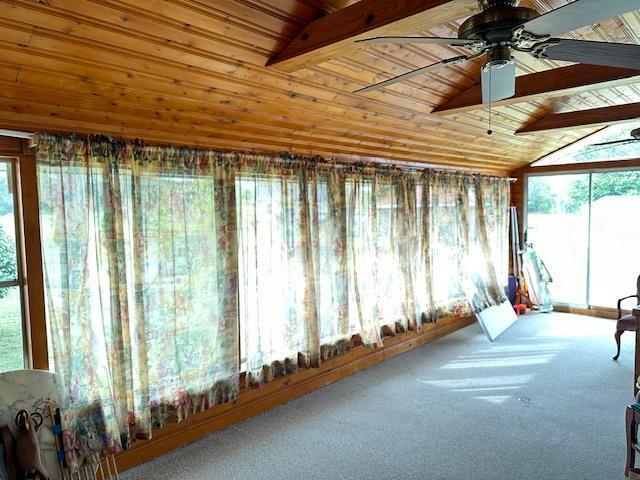 unfurnished sunroom with wooden ceiling, ceiling fan, and vaulted ceiling with beams