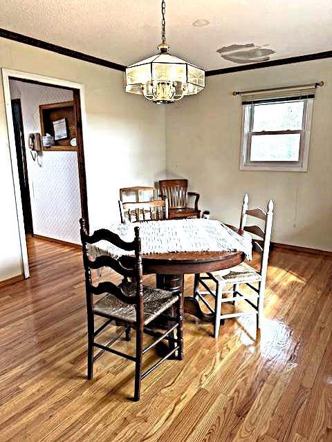 dining space with hardwood / wood-style flooring, crown molding, and a notable chandelier