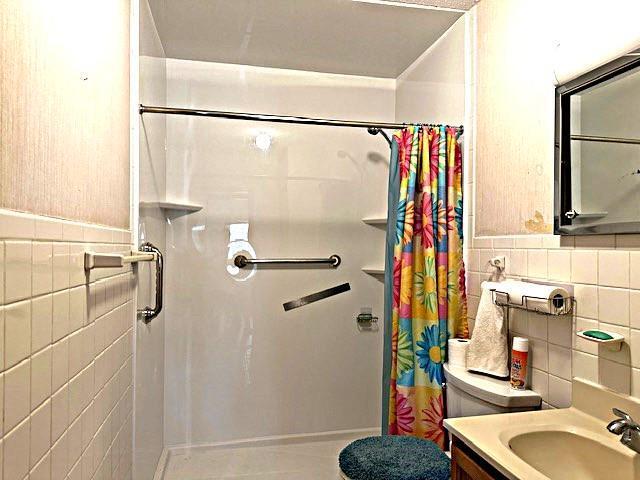 bathroom featuring vanity, tile walls, and a shower with shower curtain