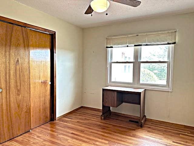 empty room featuring ceiling fan, a textured ceiling, and light wood-type flooring