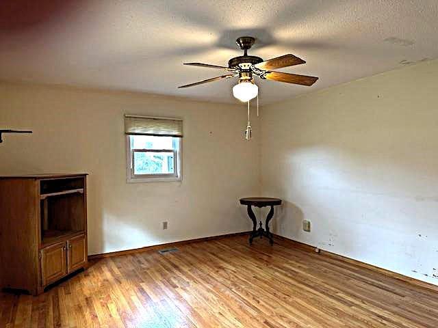 empty room with a textured ceiling, hardwood / wood-style flooring, and ceiling fan