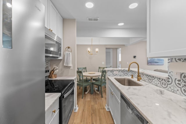 kitchen featuring stainless steel appliances, a sink, white cabinets, and light wood-style floors