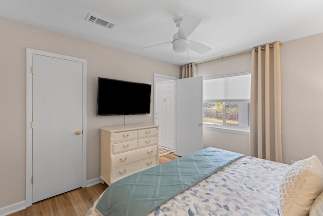 bedroom with baseboards, light wood-style flooring, visible vents, and a ceiling fan