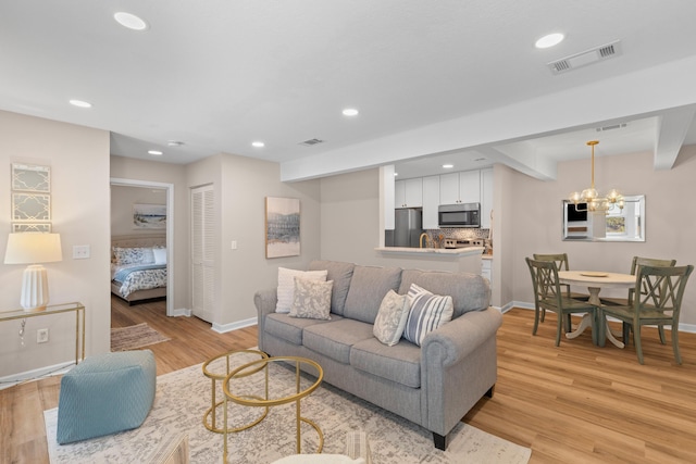 living room with recessed lighting, visible vents, light wood finished floors, beamed ceiling, and an inviting chandelier