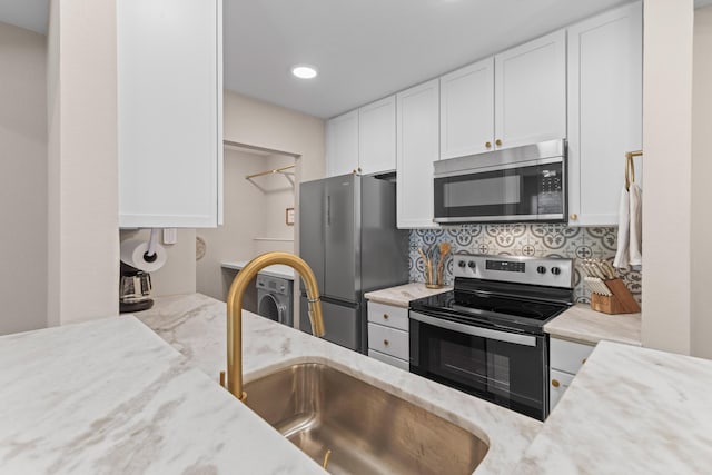 kitchen with stainless steel appliances, light stone counters, a sink, and white cabinets