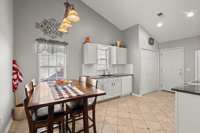 kitchen featuring hanging light fixtures, dark countertops, a sink, and white cabinets