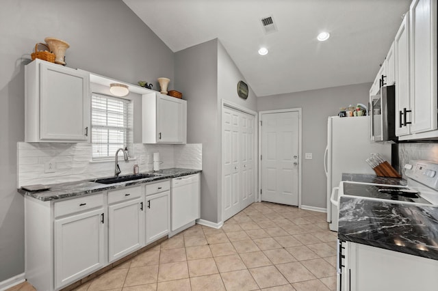 kitchen with white appliances, a sink, visible vents, white cabinetry, and vaulted ceiling