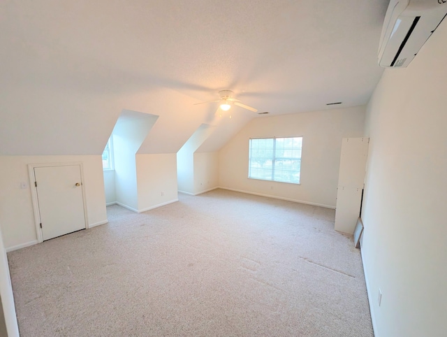 additional living space featuring vaulted ceiling, a wall mounted AC, light colored carpet, and ceiling fan