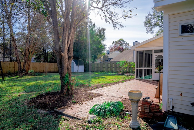 view of yard featuring a patio, a sunroom, and a storage unit